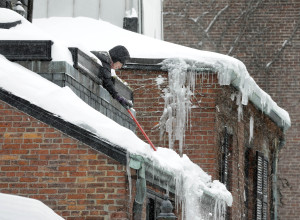 Boston homeowner clears roof. Insurers and agents are fielding ice dam questions and claims. (AP Photo/Steven Senne)