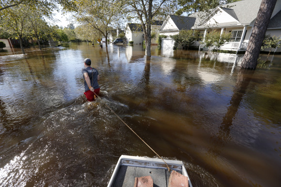 Ethan Abbott pulls his boat down Mayfield St. to help a friend get personal items out of the house in the Ashborough subdivision near Summerville, S.C., Tuesday, Oct. 6, 2015. Residents are concerned that the Ashley river will continue to rise as floodwaters come down from Columbia.  (AP Photo/Mic Smith)