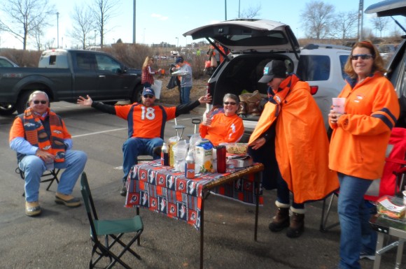 Dave Adams, in the Manning jersey, and Pam Adams, in the orange cape, are brother and sister owners of ISU Insurance Services of Colorado Inc. Here they are at a tailgate party with friends at Mile High stadium before the AFC Championship game in which the Broncos advanced against the New England Patriots in a 20-18 duel. 
