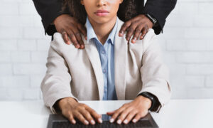 Sexual harassment problem. Closeup of boss touching his beautiful female assistant at workplace, panorama
