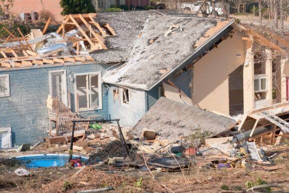 Aftermath of a tornado damaged blue wood framed house. The storm came through this residential neighborhood in March and damaged numerous houses in its path.