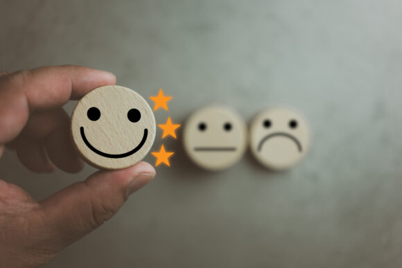 Customer satisfaction survey concept. Customer selects wooden cube with happy face icon and three star, best service excellence rating for satisfaction. Customer experience concept
