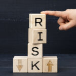 wooden cubes with the inscription risk on a blue background. Risk reduction concept, reinsurance. How to avoid losses, unknown new beginnings in business and life