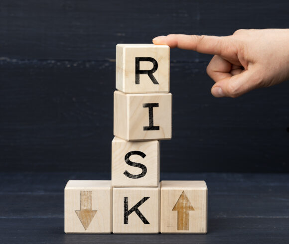 wooden cubes with the inscription risk on a blue background. Risk reduction concept, reinsurance. How to avoid losses, unknown new beginnings in business and life
