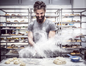 Man preparing donuts and splashing flour with his hands,selective focus
