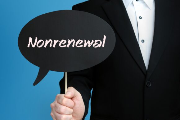 Nonrenewal. Businessman in suit holds speech bubble at camera. T