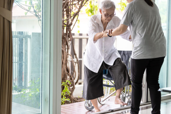 Asian caregiver help care to senior grandmother walk,woman holding hands of the old elderly for support,walking up from a different level floor,safety,prevent accident at nursing home,service concept