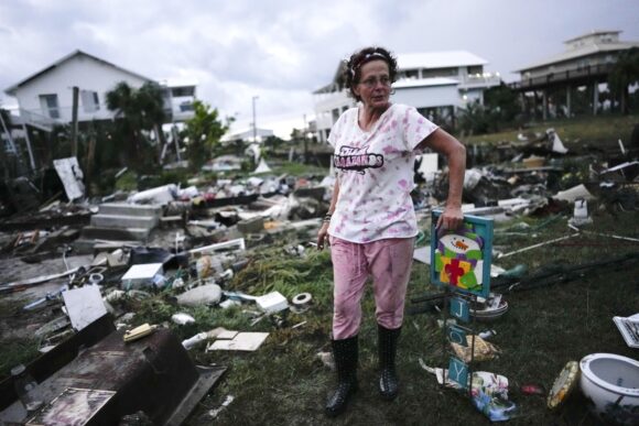 FILE - Jewell Baggett stands beside a Christmas decoration she recovered from the wreckage of her mother's home, as she searches for anything salvageable from the trailer home her grandfather had acquired in 1973 and built multiple additions on to over the decades, in Horseshoe Beach, Fla., after the passage of Hurricane Idalia, Wednesday, Aug. 30, 2023. (AP Photo/Rebecca Blackwell, File)