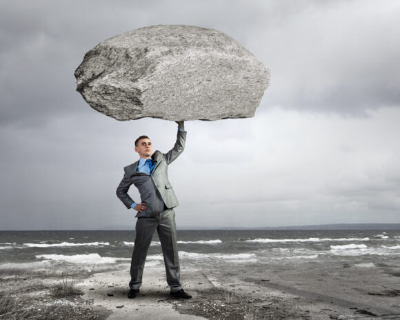 man holding a heavy boulder above his head