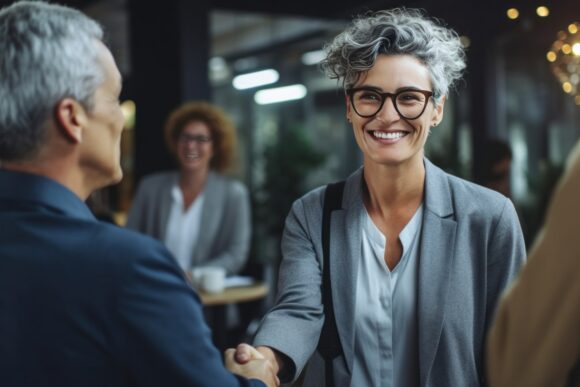 Mature businesswoman shakes hands, makes a successful deal with a partner. Happy HR exec welcomes new hire. Good results achieved. Generative AI
