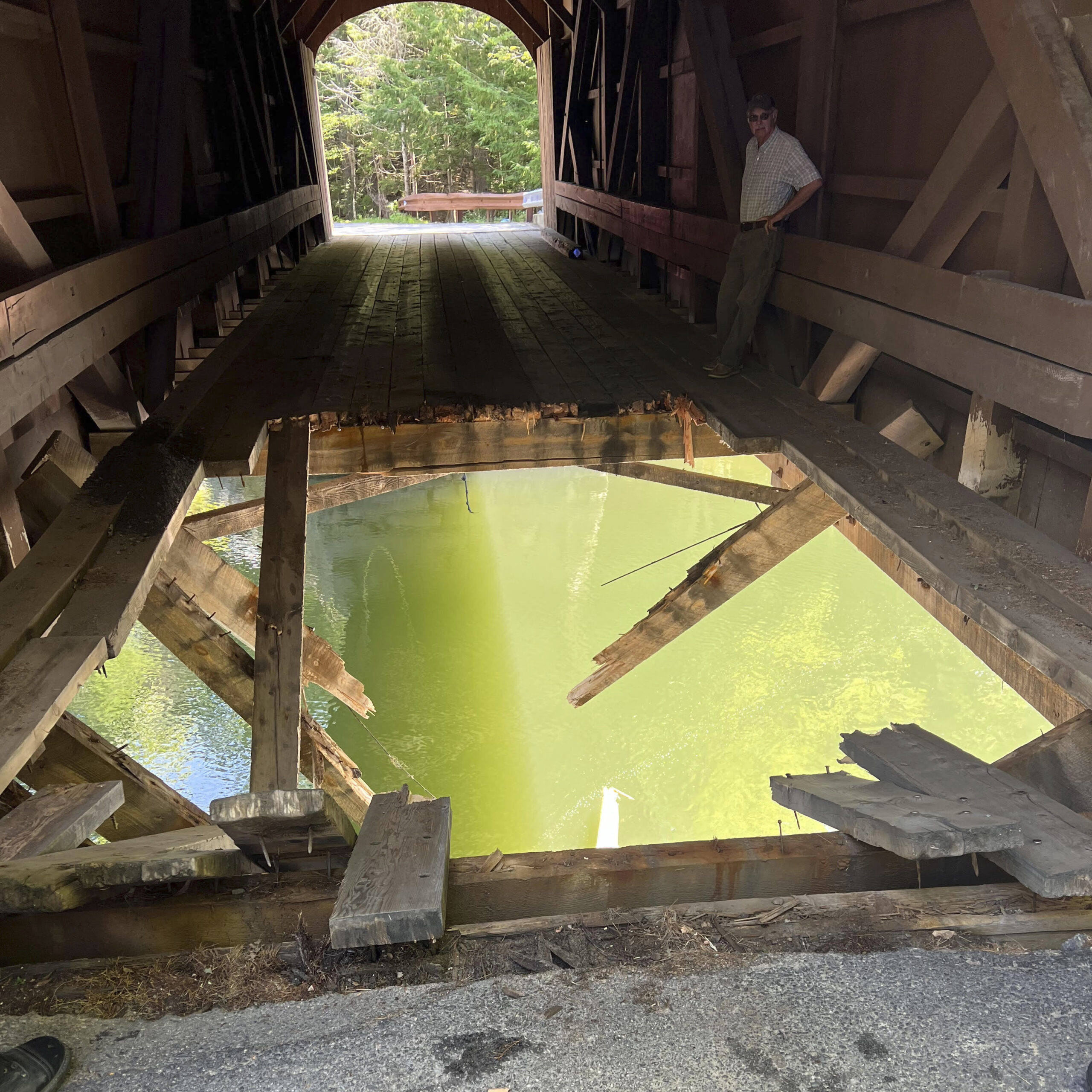 Overweight dump truck left hole in covered bridge when it plunged into river