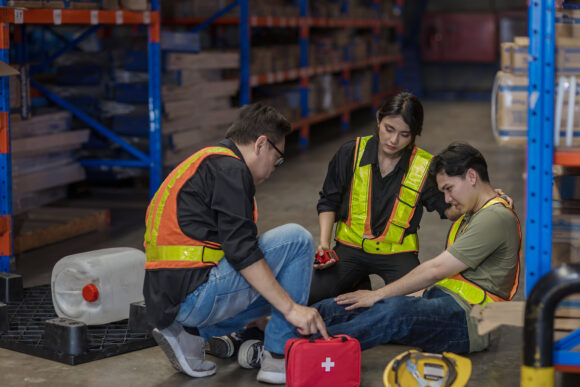 First aid support accident at work of worker at factory. Male worker has an accident on the floor in warehouse site