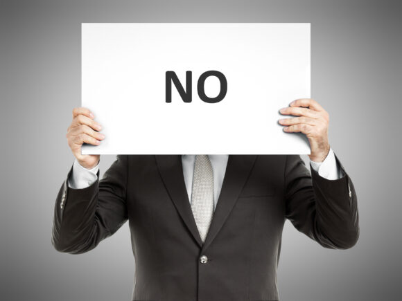 A business man holding a paper in front of his face with the word no