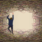 A man in a suit climbs and struggles against a tangle of colored lines of wire in an illustration about overcoming any difficult situation.